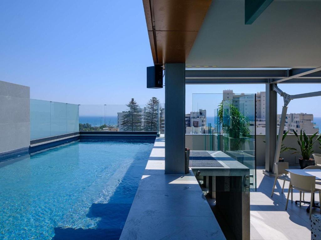 a swimming pool on the roof of a building at Mercure Larnaca Finikoudes Beach in Larnaca