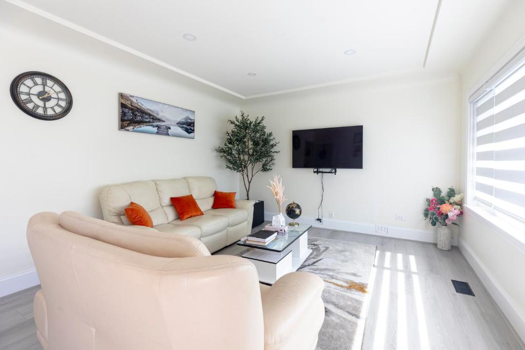 a white living room with a couch and a tv at Vancouver Cozy Cove in Vancouver