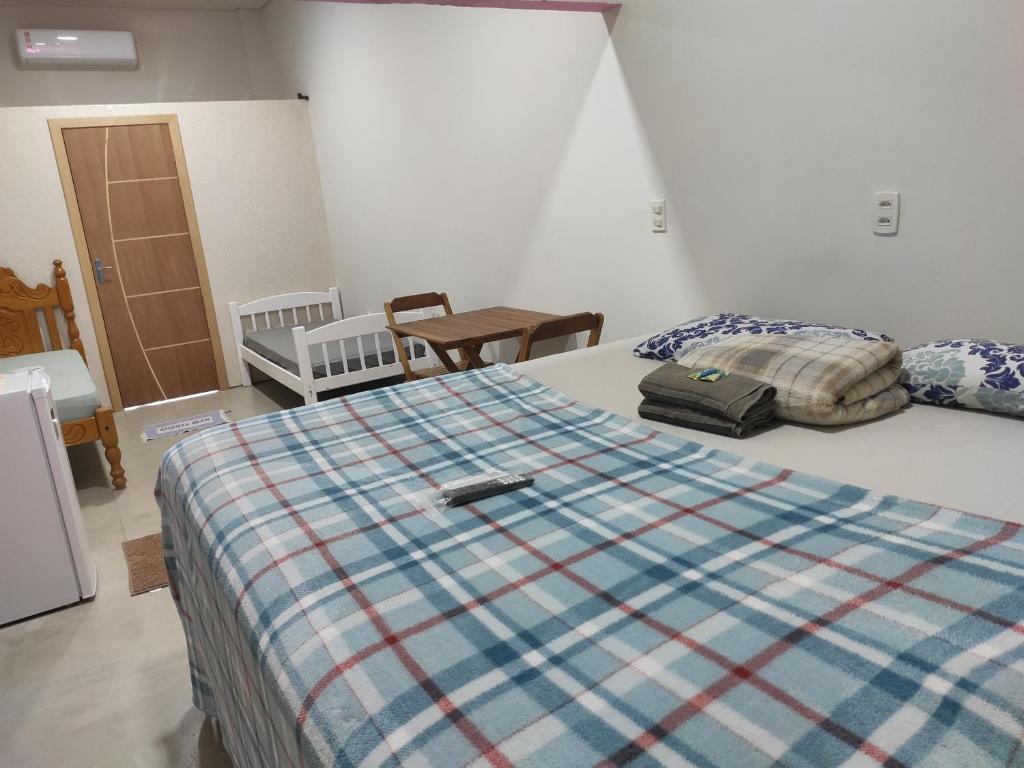 a bedroom with a bed with a plaid blanket on it at Apartamento Nami 2 in Cacoal