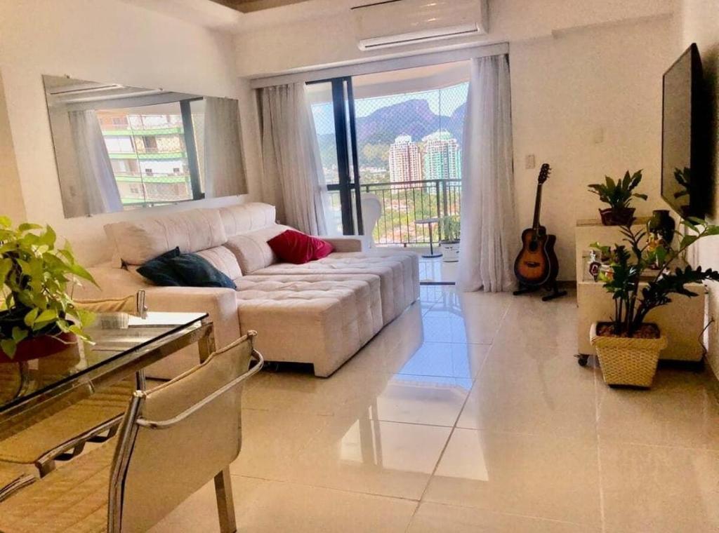 een woonkamer met een witte bank en een gitaar bij Condomínio Four Seasons Residence Service in Rio de Janeiro