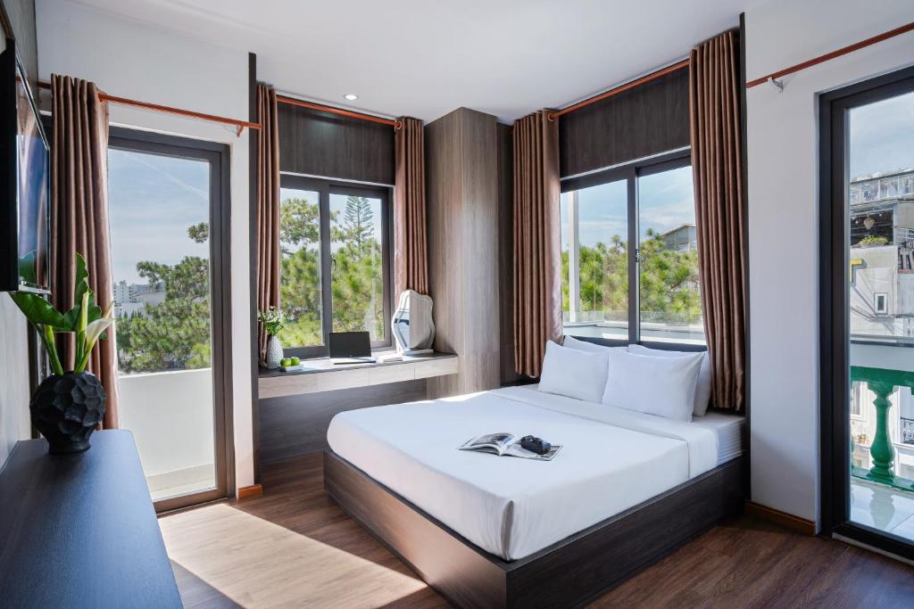 a bedroom with a white bed and two windows at ELC Luxury Đà Lạt in Da Lat