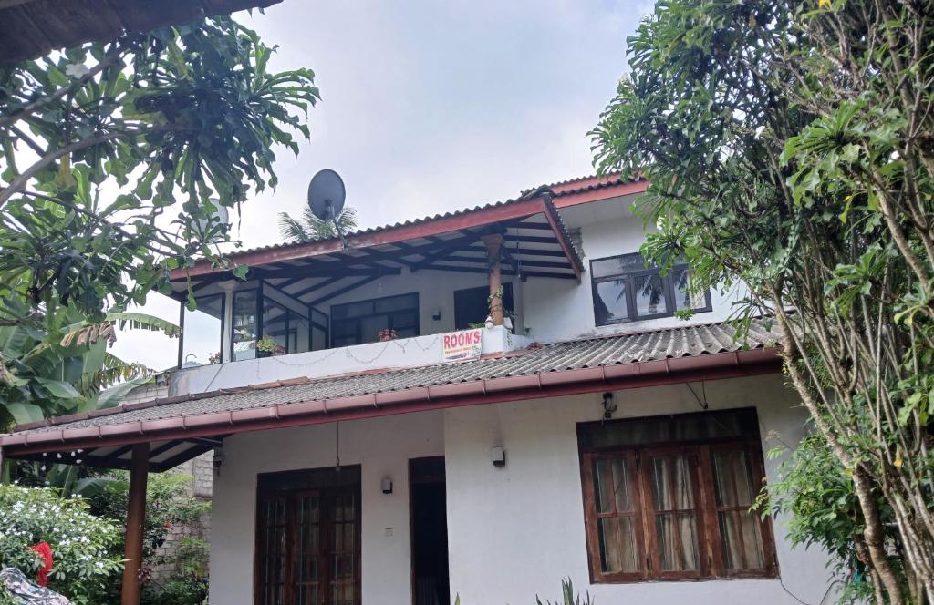 a white house with a red roof and trees at Kumari villa in Weligama