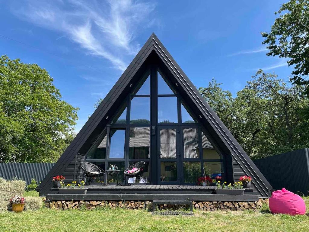 a house with a triangular roof with two chairs and flowers at Серце Карпат in Skole