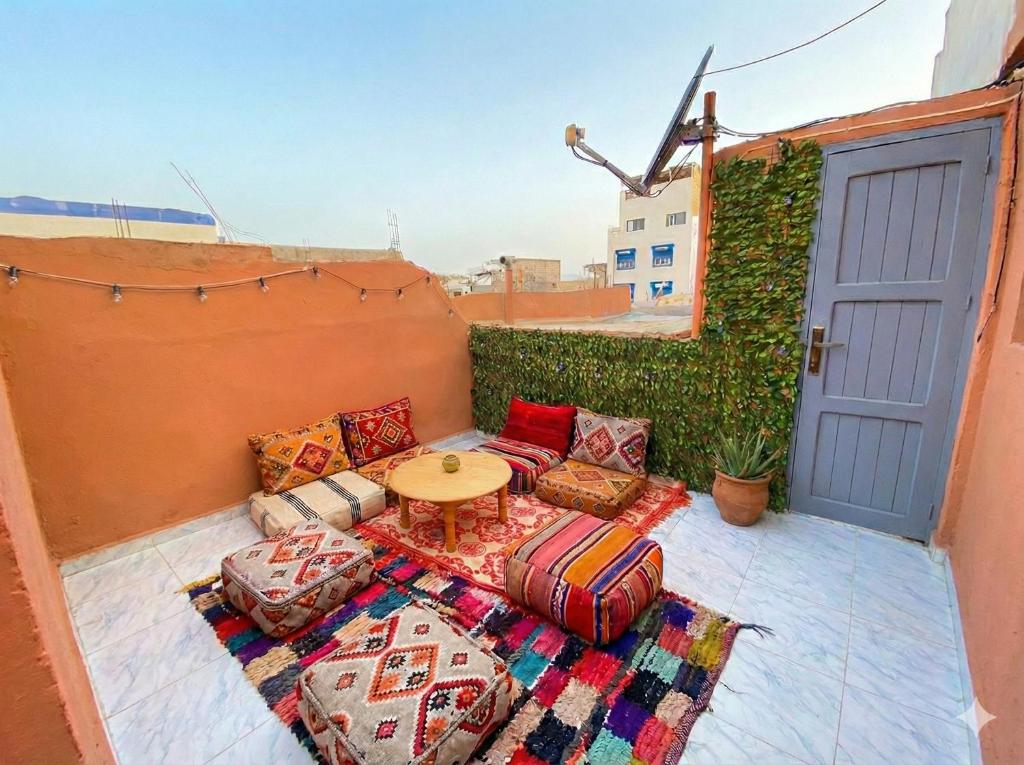 a patio with a table and some pillows and a table at Entire Guesthouse with Private Rooftop in Taghazout