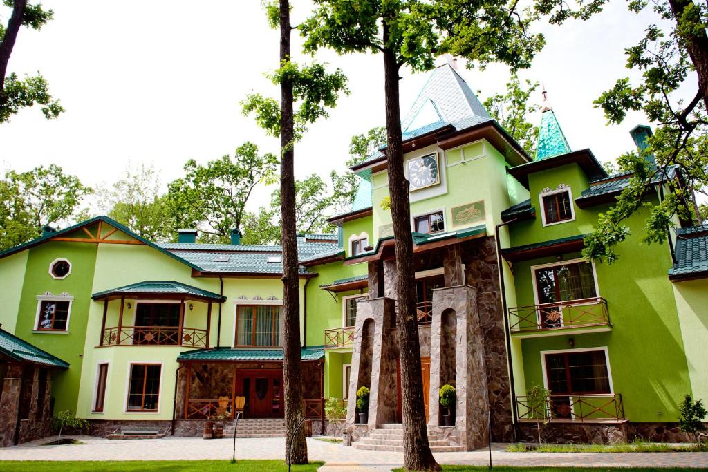 une maison verte et jaune avec des arbres devant elle dans l'établissement Recreation Complex Gostevia, à Strizhavka