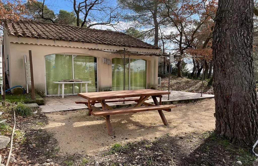 une table de pique-nique en bois devant une maison dans l'établissement Maison confortable à Velleron de 50 m² avec piscine, à Velleron