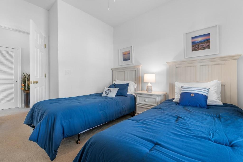 2 bedden in een slaapkamer met blauwe lakens bij Stylish Barefoot Golf Condo with Pool Access in North Myrtle Beach