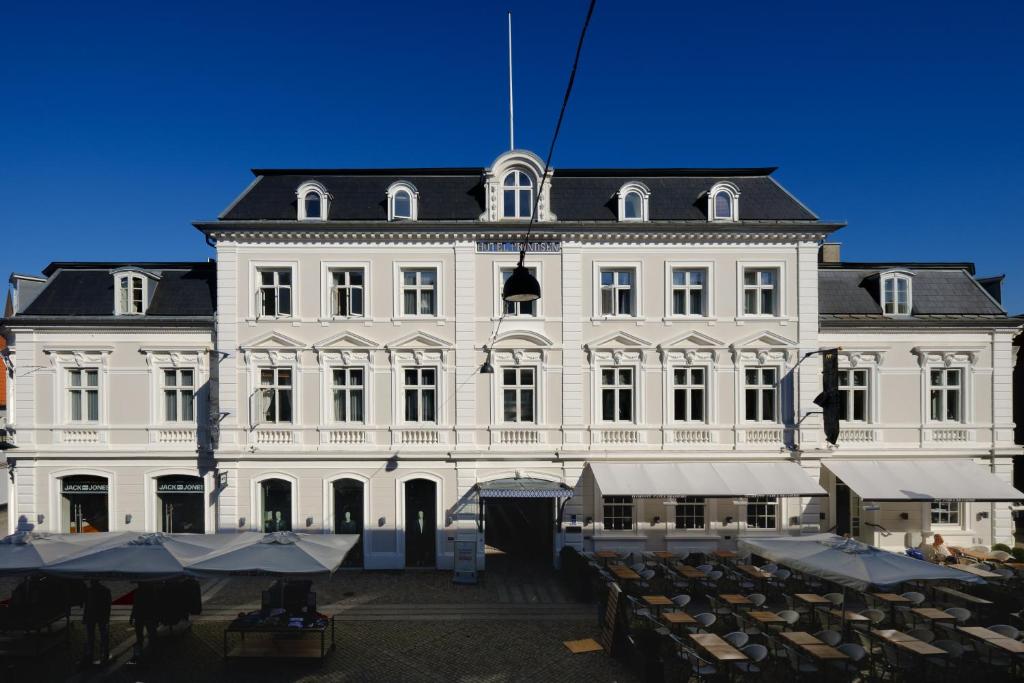 a large white building with tables in front of it at Zleep Hotel Prindsen Roskilde in Roskilde