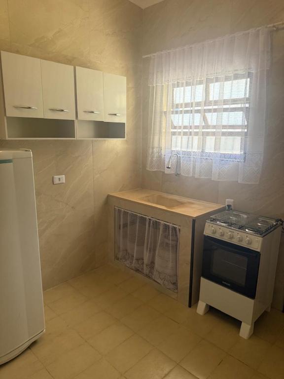 a small kitchen with a stove and a window at Anjos in Ilha Comprida