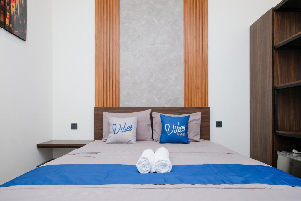 un letto con due paia di scarpe bianche sopra di Vibes Djanti Residence Yogyakarta By Sans Hotel a Demangan