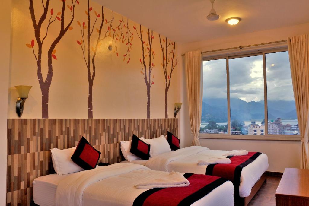 2 letti in una stanza con alberi sul muro di Hotel City Inn - Mountain View a Pokhara