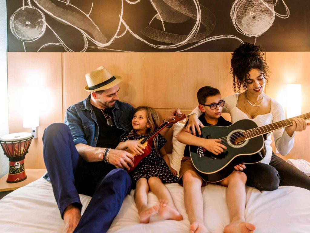 a group of people sitting on a bed playing guitar at ibis Avignon Centre Gare in Avignon