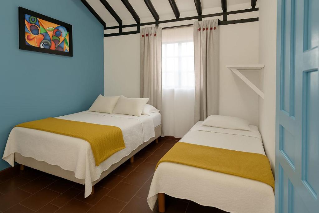 2 Betten in einem blau-weißen Zimmer in der Unterkunft CASA NOCHE AZUL alojamiento turístico in Villa de Leyva