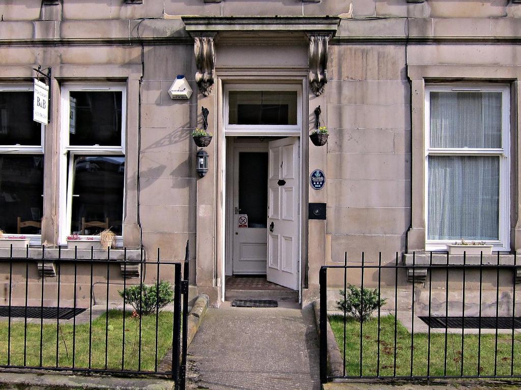 un edificio con una puerta blanca y un gato sentado en la ventana en McCrae's Bed and Breakfast, en Edimburgo