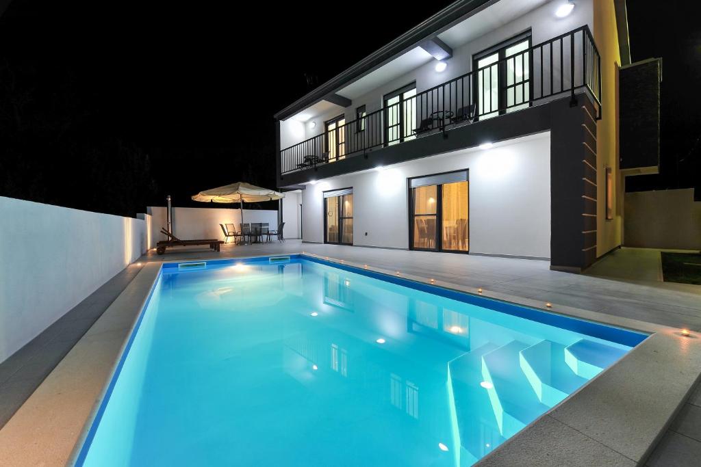 a swimming pool in front of a house at night at Villa Lily in Privlaka
