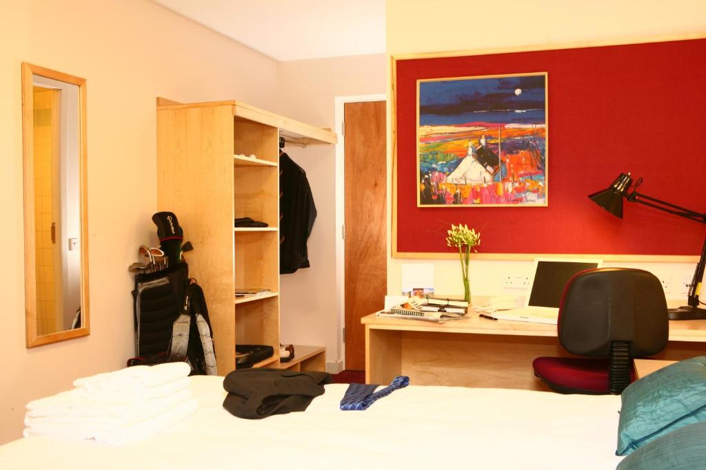 Dormitorio con cama, escritorio y pintura en David Russell Hall - Campus Accommodation en St Andrews