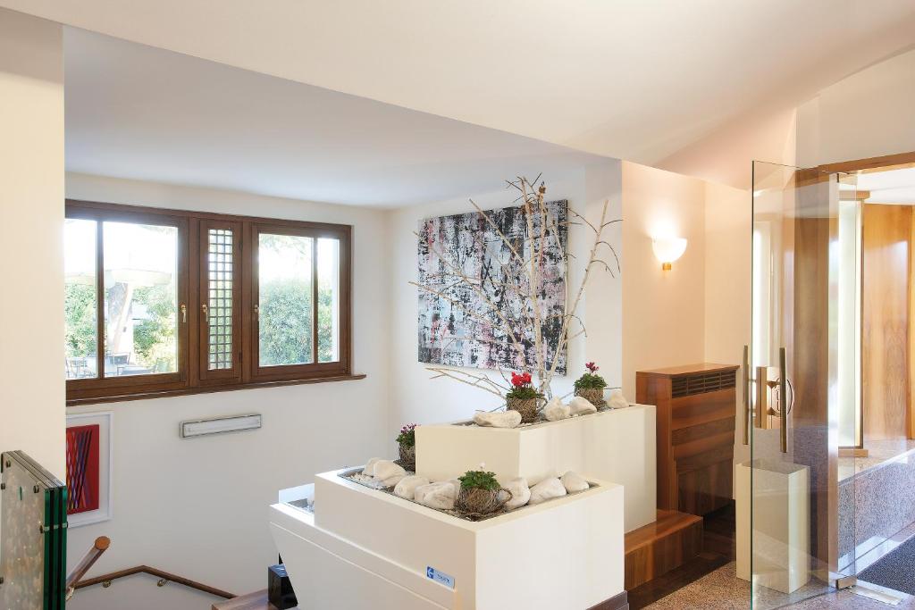 baño con paredes blancas, ventanas y plantas en Hotel Campiello, en San Giovanni al Natisone