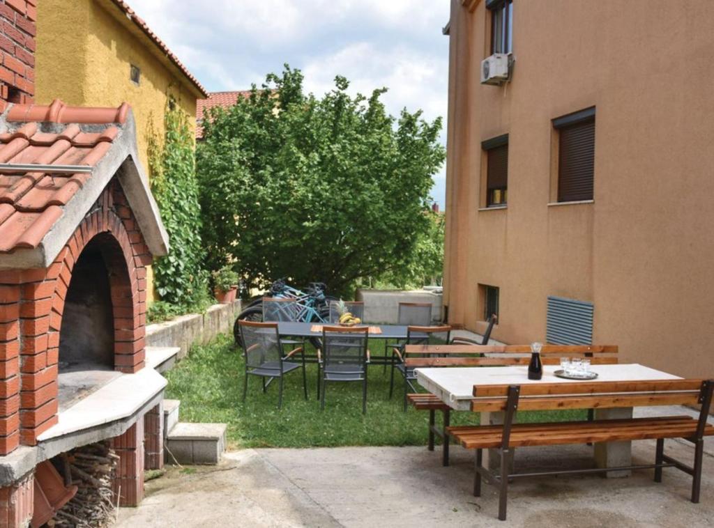 een terras met tafels en stoelen en een steenoven bij Sobe Melada in Trilj