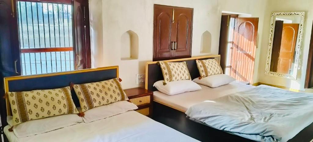 een slaapkamer met twee bedden en een raam bij Khurja Wali Dharamshala in Rishīkesh