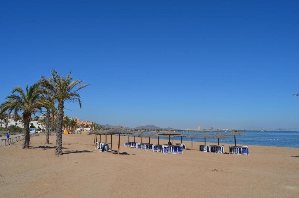 una playa con sillas, sombrillas y palmeras en Villa Cristal 9907 - Resort Choice, en Playa Paraiso