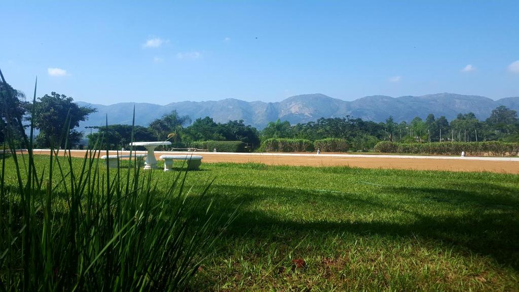 a grassy field with a road and mountains in the background at Benka LifeStyle Country Cottages in Ezulwini