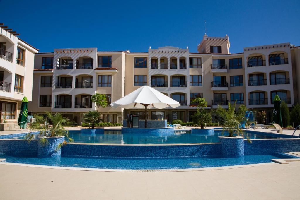 een hotel met een zwembad met een parasol bij Bay Apartments Sozopol in Sozopol