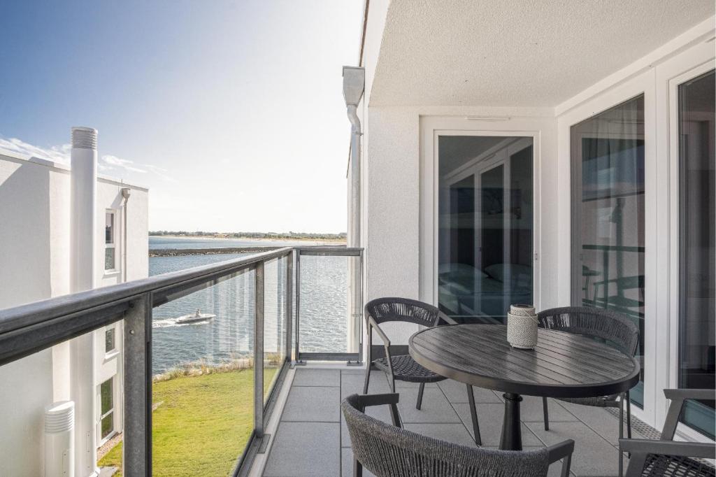 a balcony with a table and chairs and the water at Seeluft Olpenitz in Olpenitz