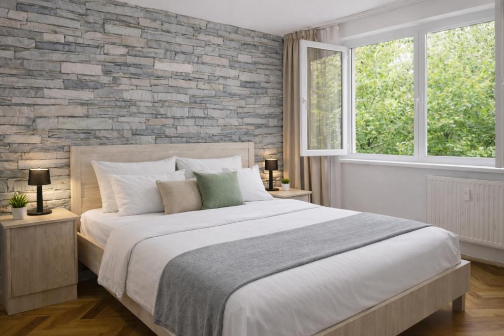 una camera con un grande letto e due finestre di Comfort 14 Stylish City Apartment a Miskolc