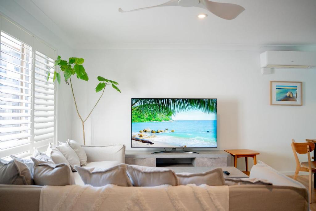 a living room with a couch and a flat screen tv at Paws & Palms Hideaway in Nelson Bay