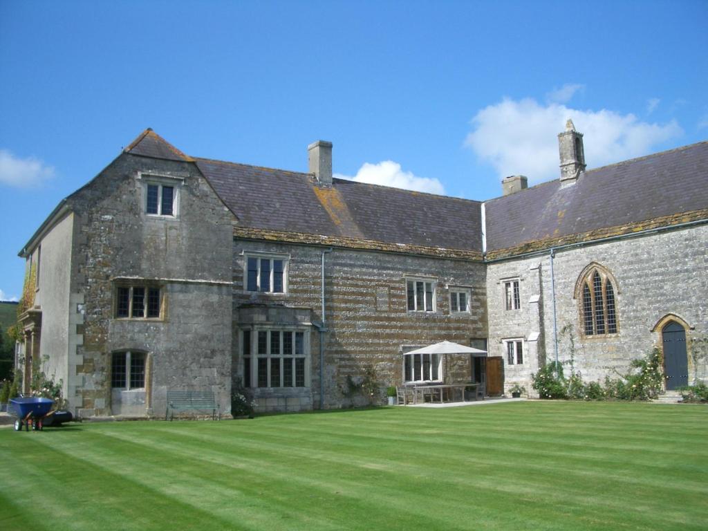 安斯蒂的住宿－Higher Melcombe Manor，一座古老的石头建筑,有大草地庭院