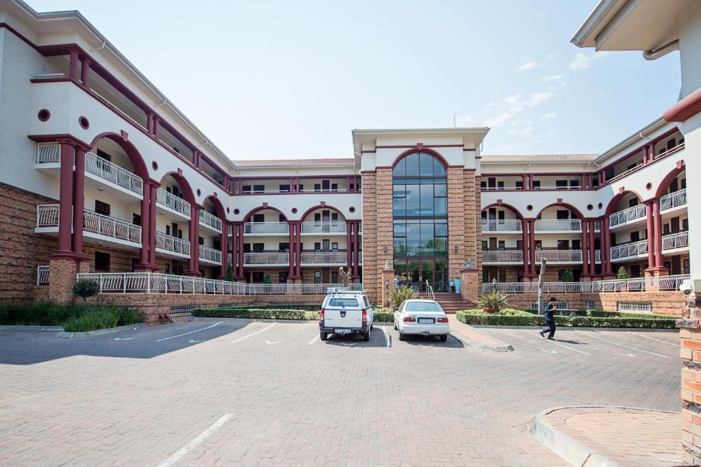 a large building with two cars parked in a parking lot at Sandton Times Square in Johannesburg