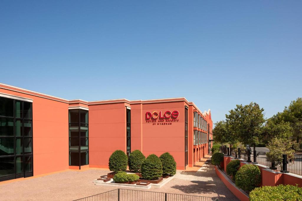 een exterieurfoto van een gebouw met een Aania-bord erop. bij Dolce by Wyndham Barcelona Resort in Sant Esteve Sesrovires