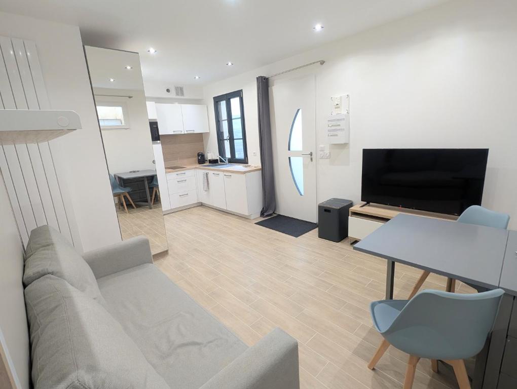een woonkamer met een bank en een tafel en een keuken bij Studio cosy et équipé proche Paris in Saint-Leu-la-Forêt