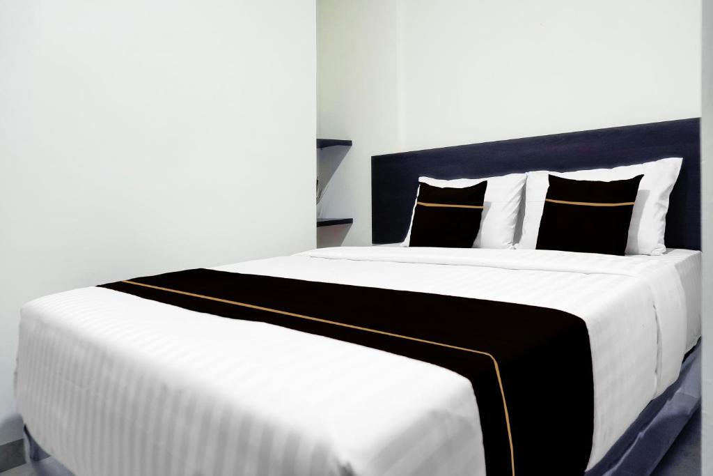 un grande letto bianco con cuscini bianchi e neri di Hotel O Khan House Syariah a Padang