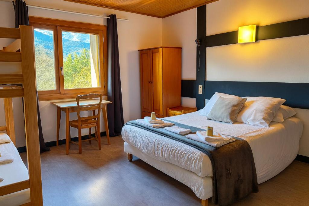 een slaapkamer met een bed, een tafel en een bureau bij Logis Hôtels La Crémaillère in Saint-Bonnet-en-Champsaur