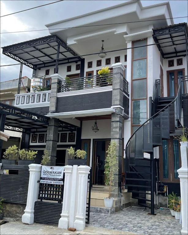 a large white house with a balcony and stairs at Utama Guest House Kuta Alam in Banda Aceh