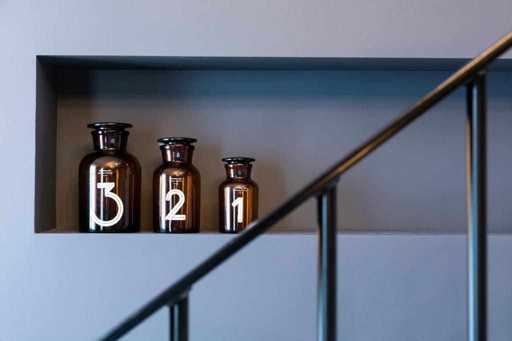 three bottles sitting on a shelf with the number sixteen at Hôtel Square Louvois in Paris