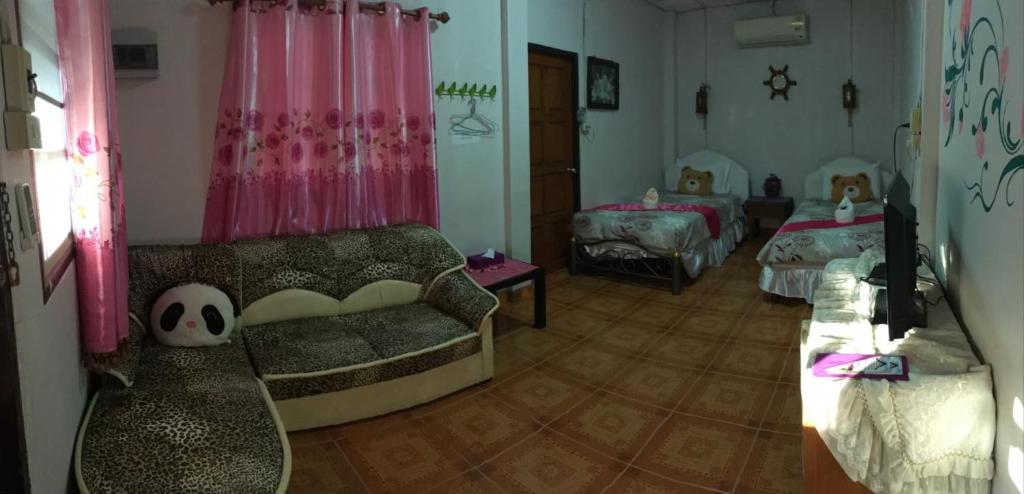 a living room with a couch and two beds at บ้านพักสายรุ้ง เพรชรบุรี in Tha Chang