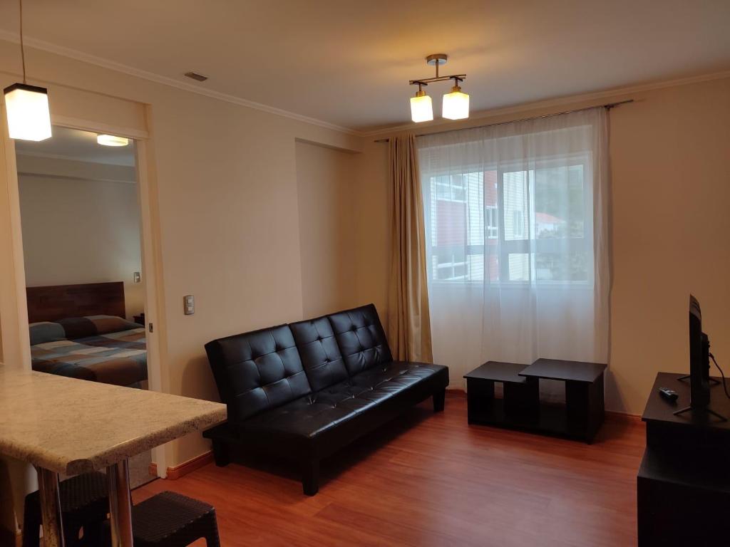 a living room with a black leather chair and a couch at Privado y Acogedor in Puerto Montt
