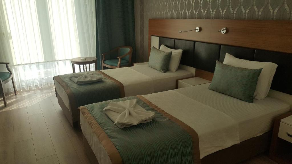 a hotel room with two beds and a chair at Hotel Kabacam Aydin in Aydın