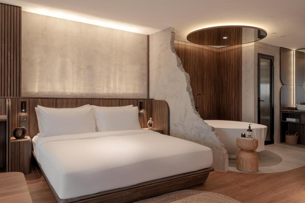 ein Schlafzimmer mit einem großen weißen Bett und ein Badezimmer in der Unterkunft The Cara Hotel in Kota Kinabalu