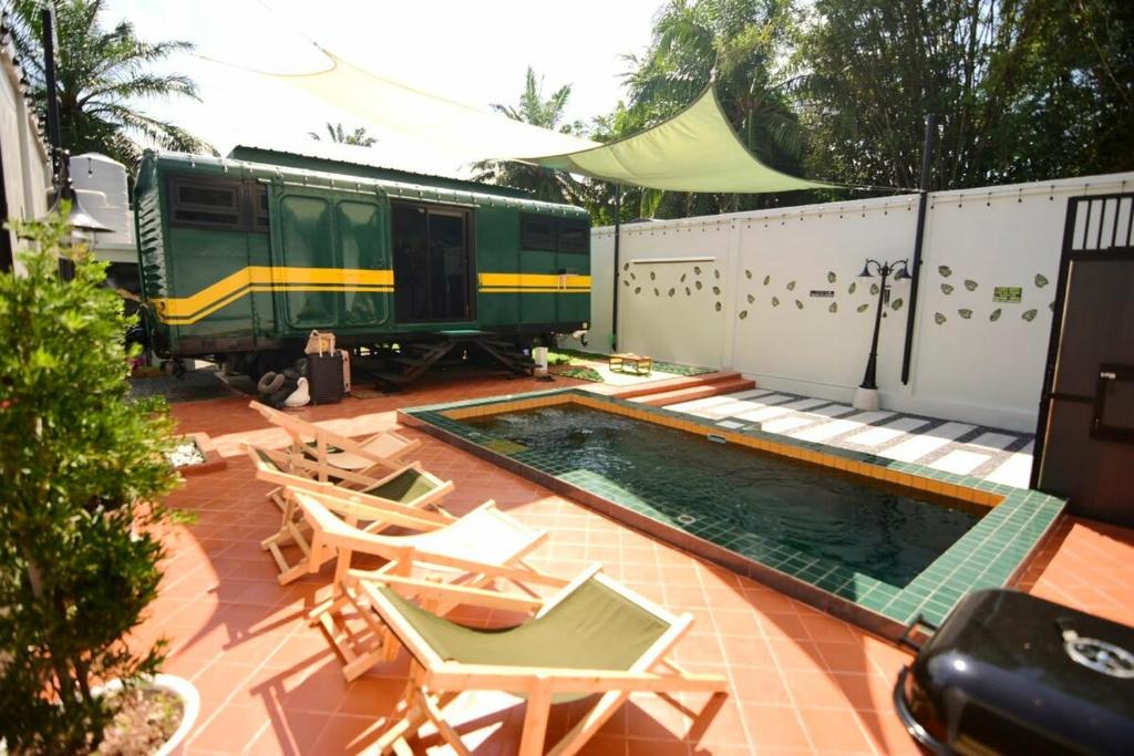 een zwembad naast een trein en een paar stoelen bij Baan Rot Fai Krabi Platform 2 in Ao Nam Mao