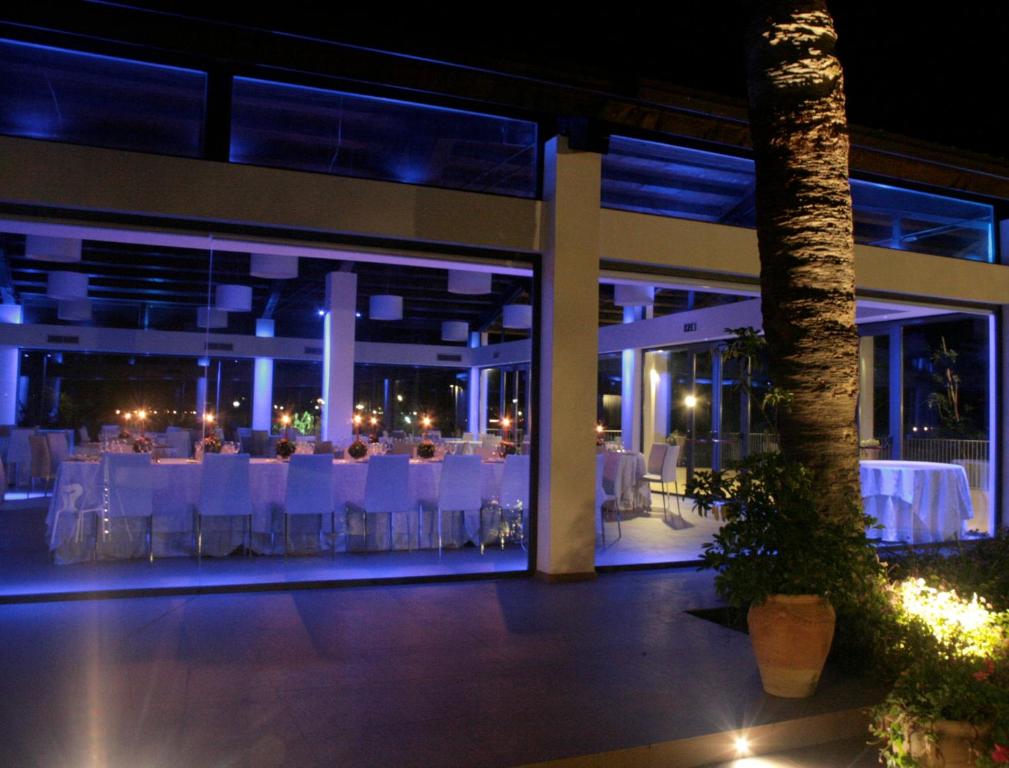 a banquet hall with white tables and chairs at night at Il Vigneto Resort in Menfi