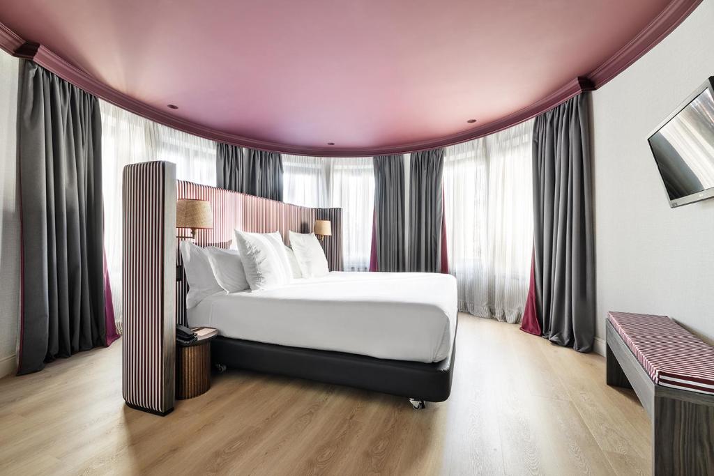 Schlafzimmer mit einem großen Bett vor den Fenstern in der Unterkunft One Shot Luchana in Madrid