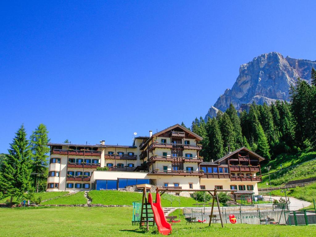 um grande edifício de apartamentos nas montanhas com um parque infantil em Hotel San Martino em San Martino di Castrozza