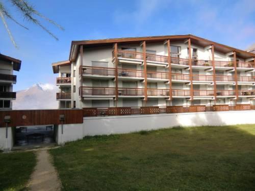 a large apartment building with a lawn in front of it at Petit studio Les 2 Alpes in Les Deux Alpes