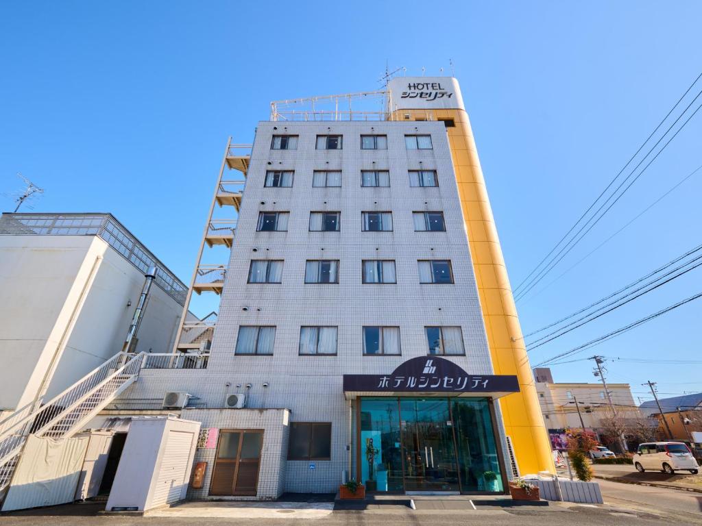 a tall white building with a doorway in front of it at Hotel Sincerity kani in Kani