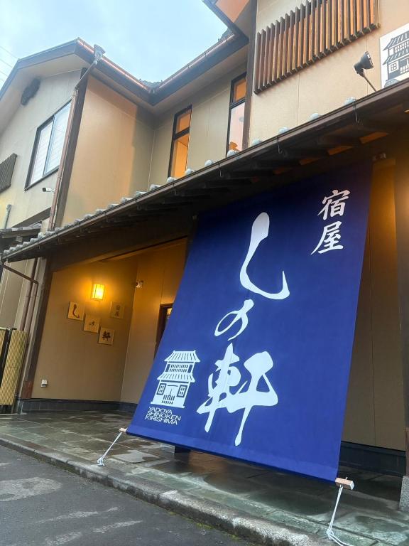 een blauw bord aan de zijkant van een gebouw bij 宿屋しの軒 1階 in Kirishima