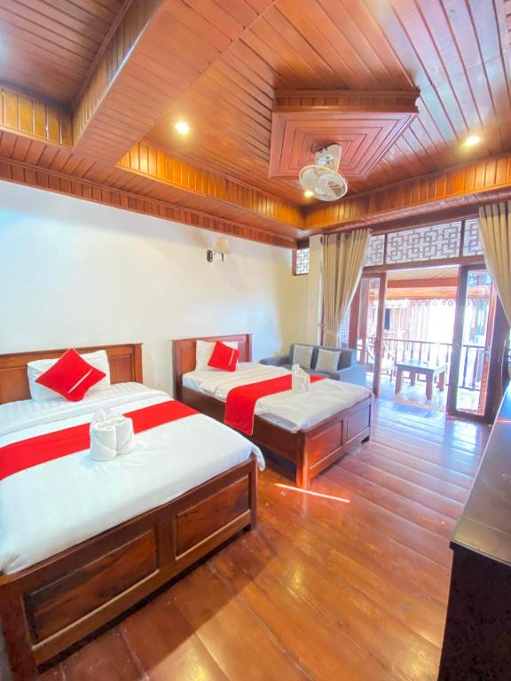a room with two beds and a couch in it at Villa Xiengthong Garden View Hotel in Luang Prabang