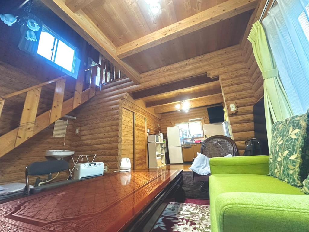 a living room with a green couch and a kitchen at コテージ杏庵 Cottage Anzuan in Minamioguni
